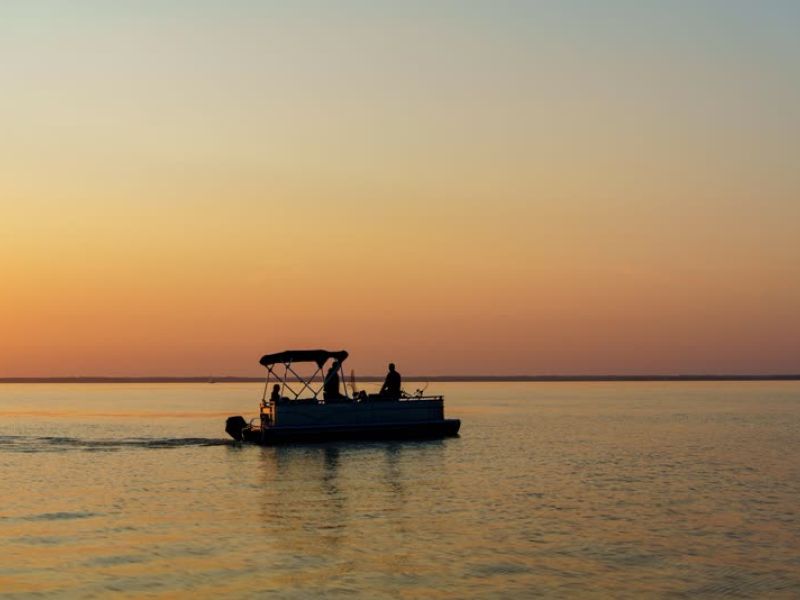 Fishing boat silhouetted against colorful sunset sky