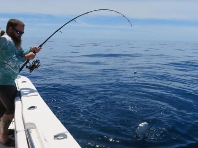 Fisherman casting line from boat in ocean