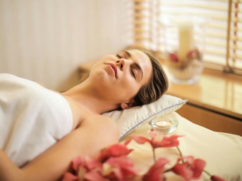 Woman receiving relaxing spa facial treatment with flowers