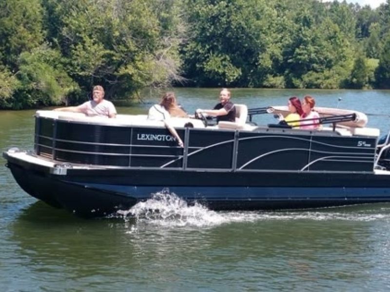 Black pontoon boat cruising on river