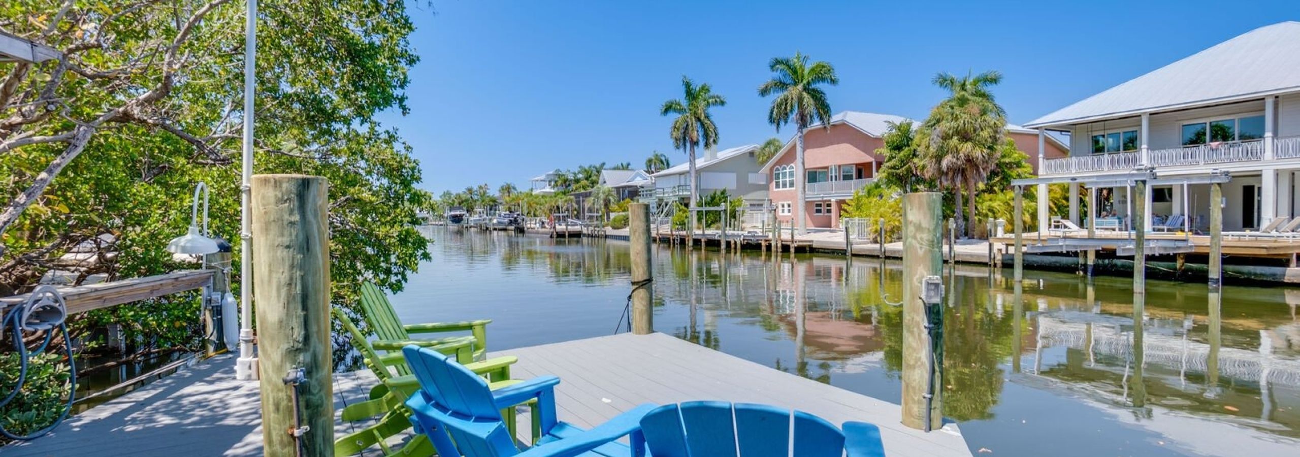 Blue Adirondack chairs on dock overlooking waterfront homes