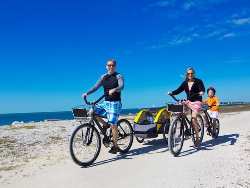 People riding bikes with trailer on sandy beach