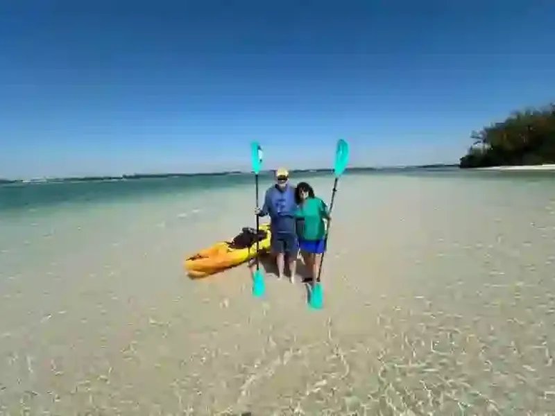 Family holds surfboards in shallow beach water