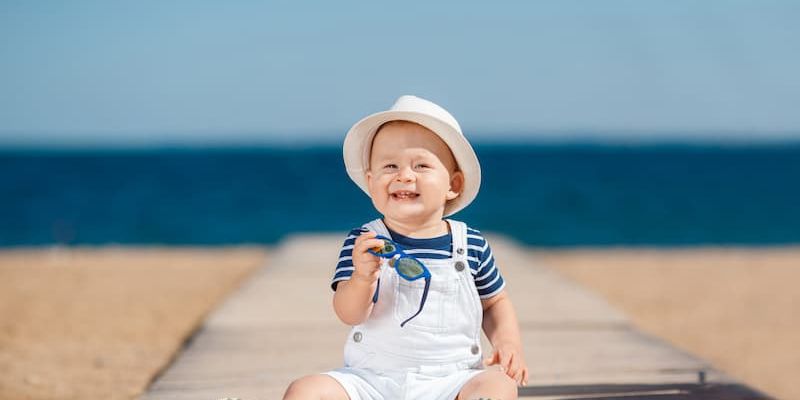 Child in white outfit on boardwalk at beach