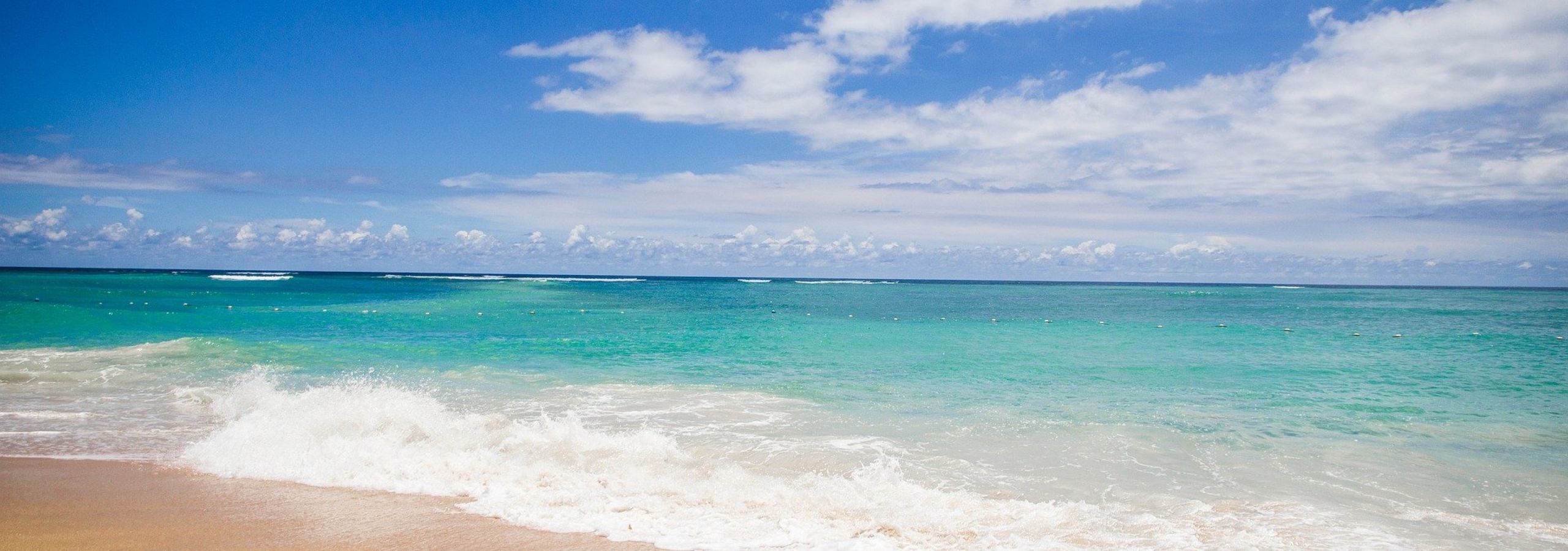 Turquoise water lapping sandy beach under blue sky
