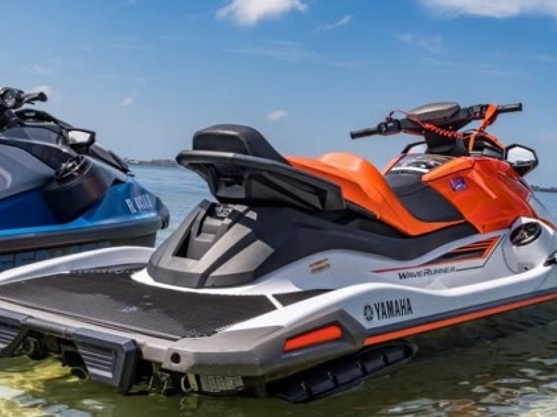 Three jet skis lined up in shallow water