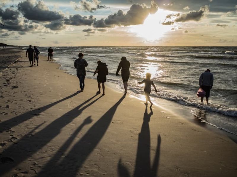 People walking on beach at golden hour sunset