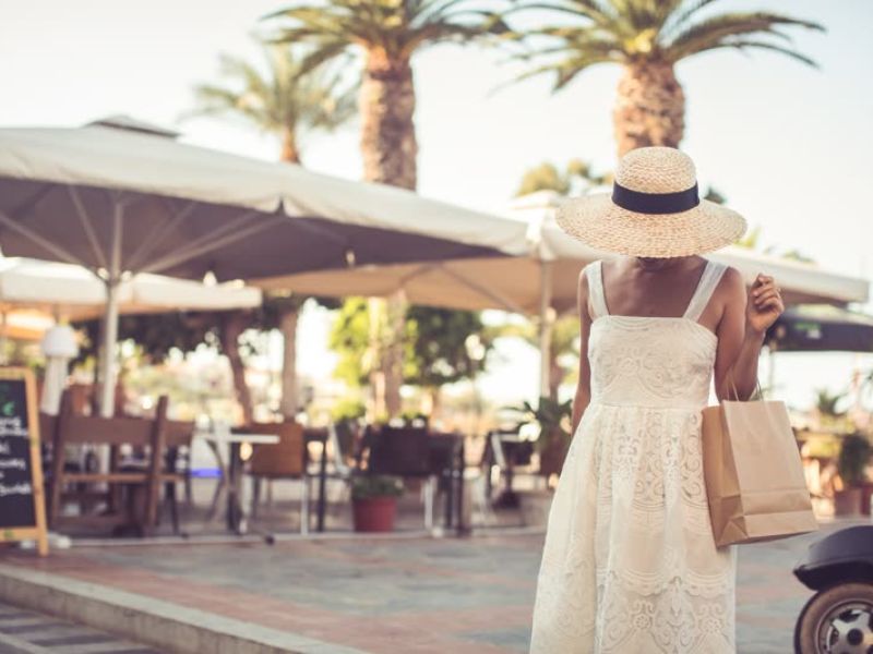 Woman in white dress at beachside bar with palm trees