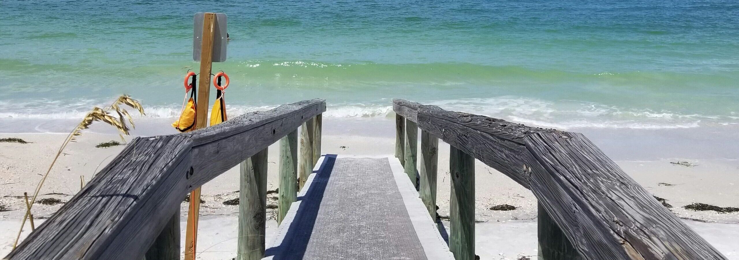 Boardwalk stretching toward pristine white sand and turquoise water