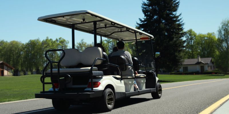 People ride golf cart on a golf course