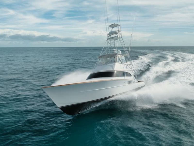 White offshore fishing boat moving through blue ocean water