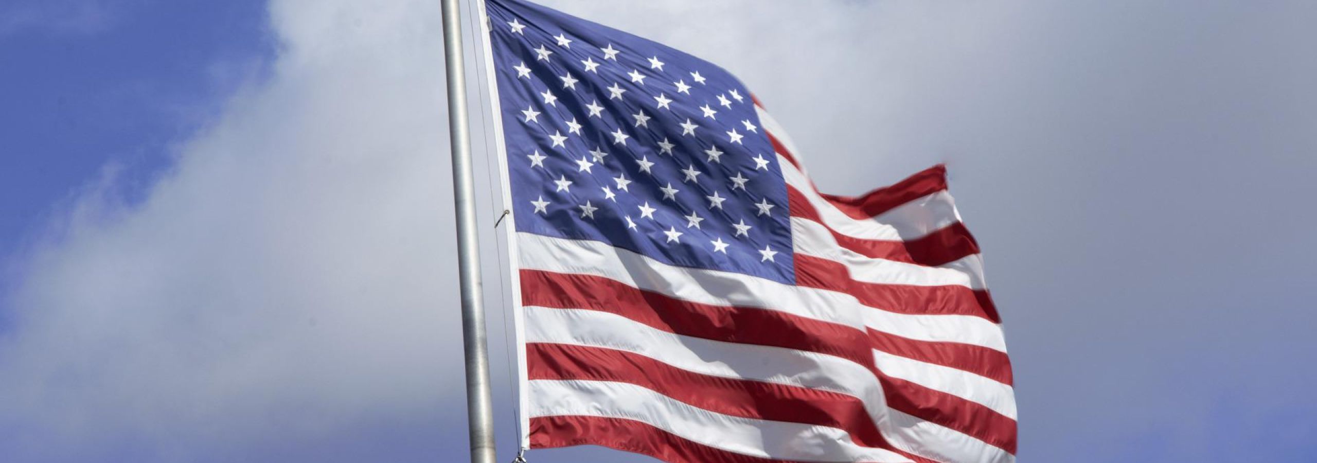 American flag waving against blue cloudy sky