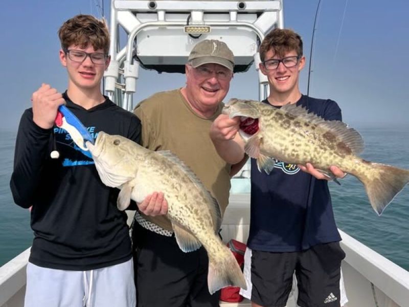 Anglers holding fish on fishing boat