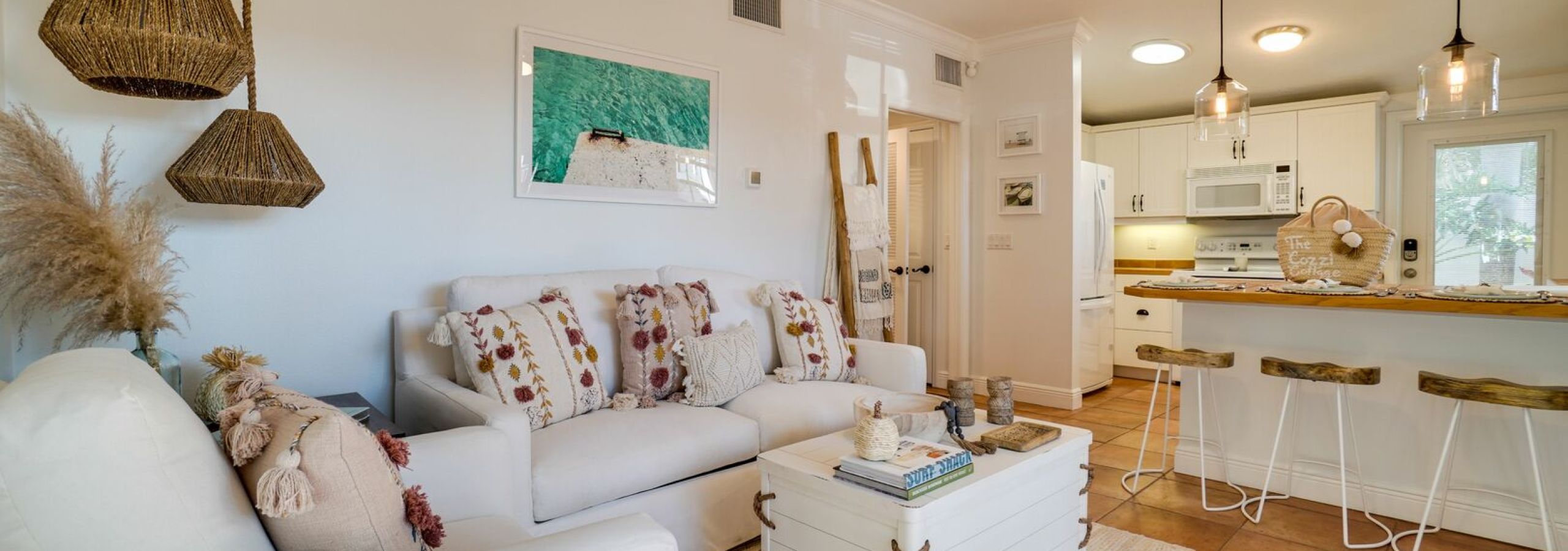 Bright living room in vacation rental with gray sofa and kitchen