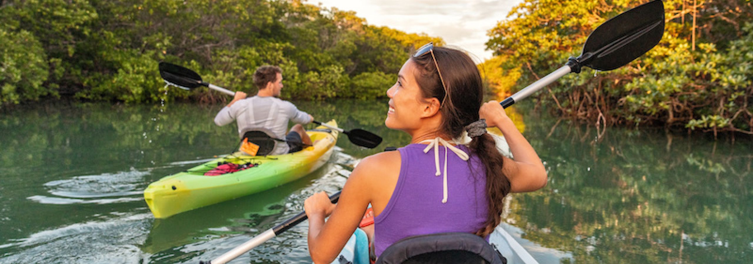 Woman paddling kayak through lush mangrove forest