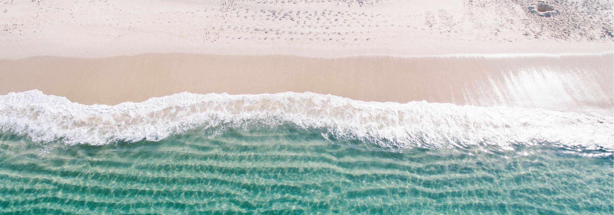 Aerial view of turquoise waves meeting sandy beach