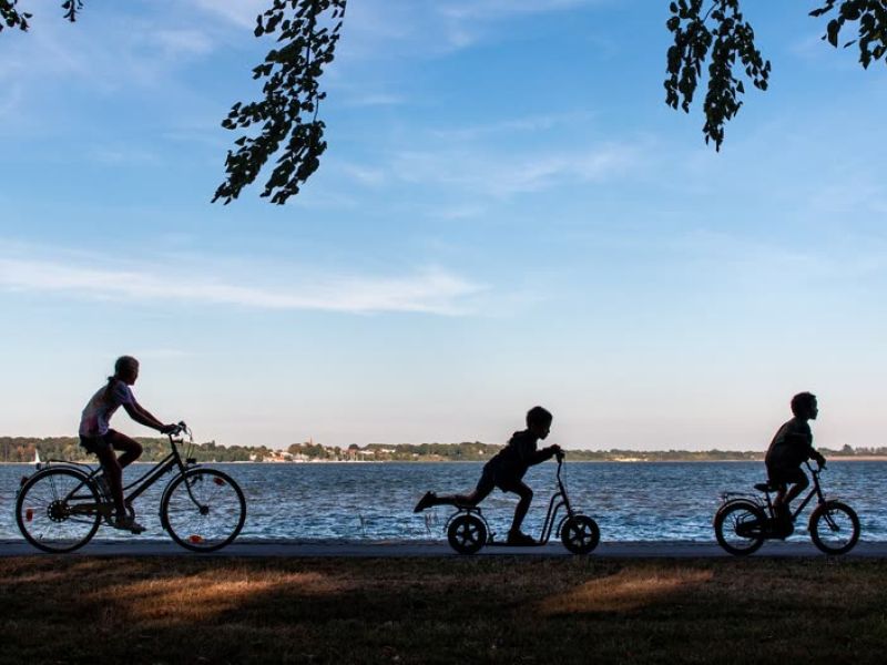 Three people riding bikes along waterfront promenade