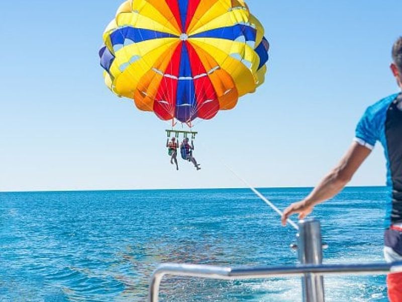 Two people parasailing with colorful parachute overhead