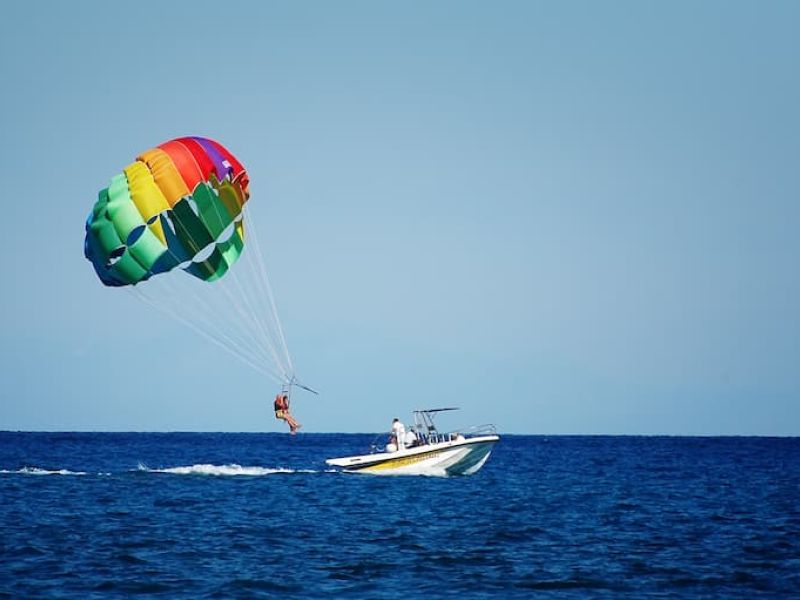 Colorful parasail inflated above water behind boat