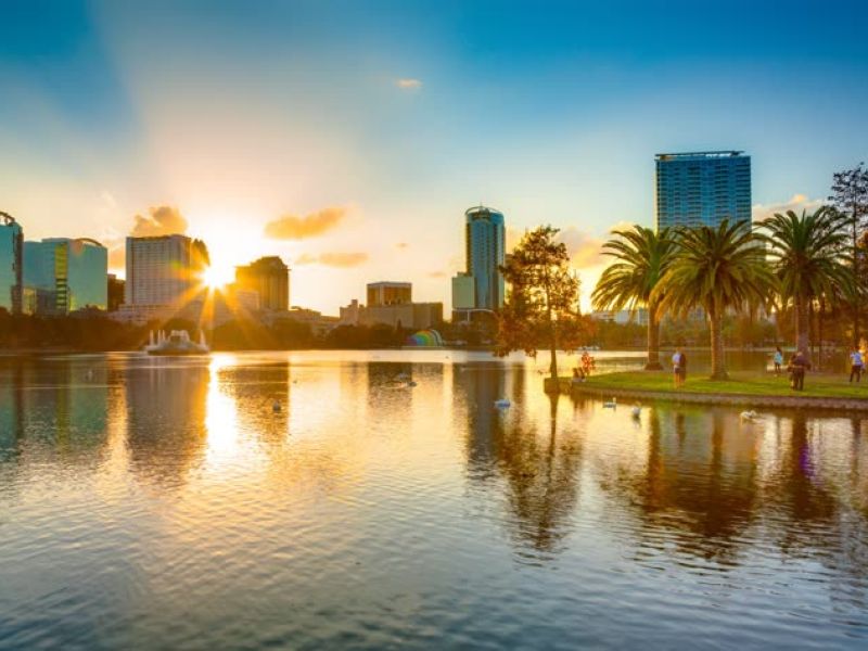 City skyline reflected in water at sunset with palm trees