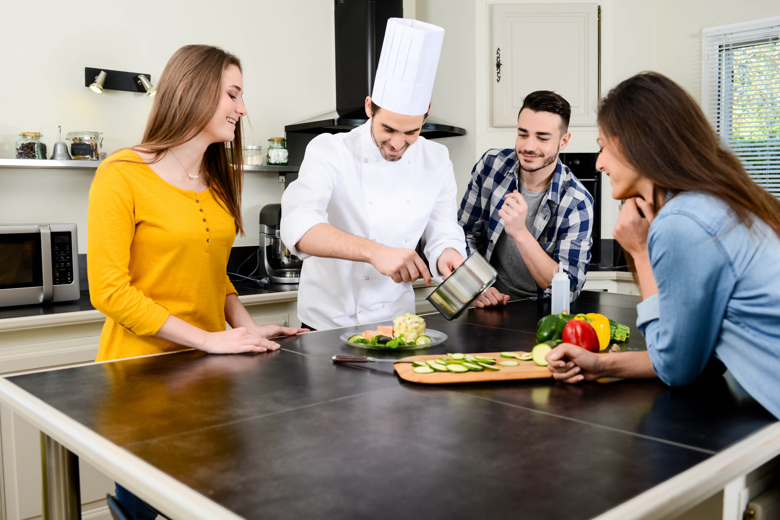 professional personal chef cook in customer's private kitchen house giving cooking lesson to young people at home