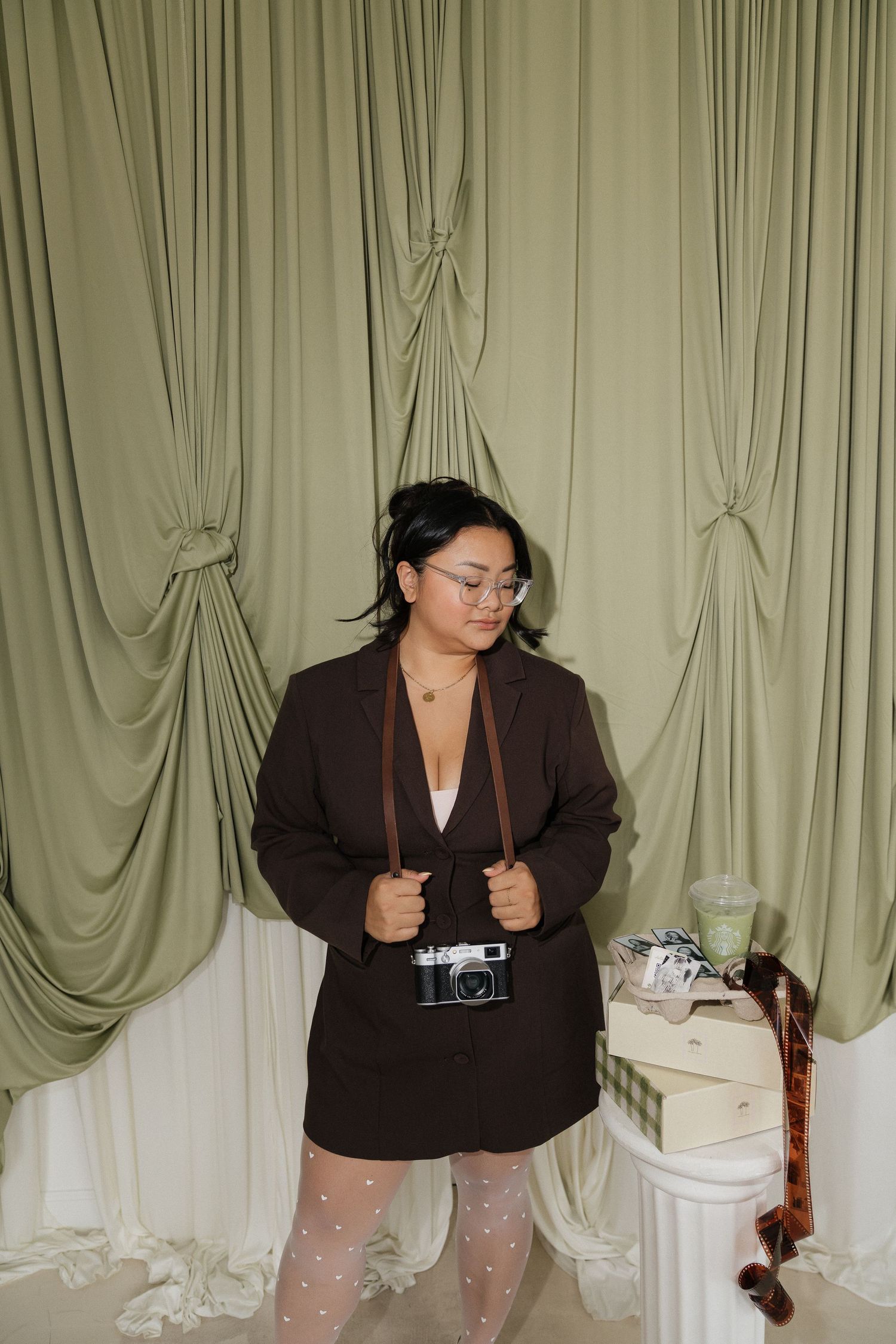Victoria Nguyen holding a film camera in a brown blazer