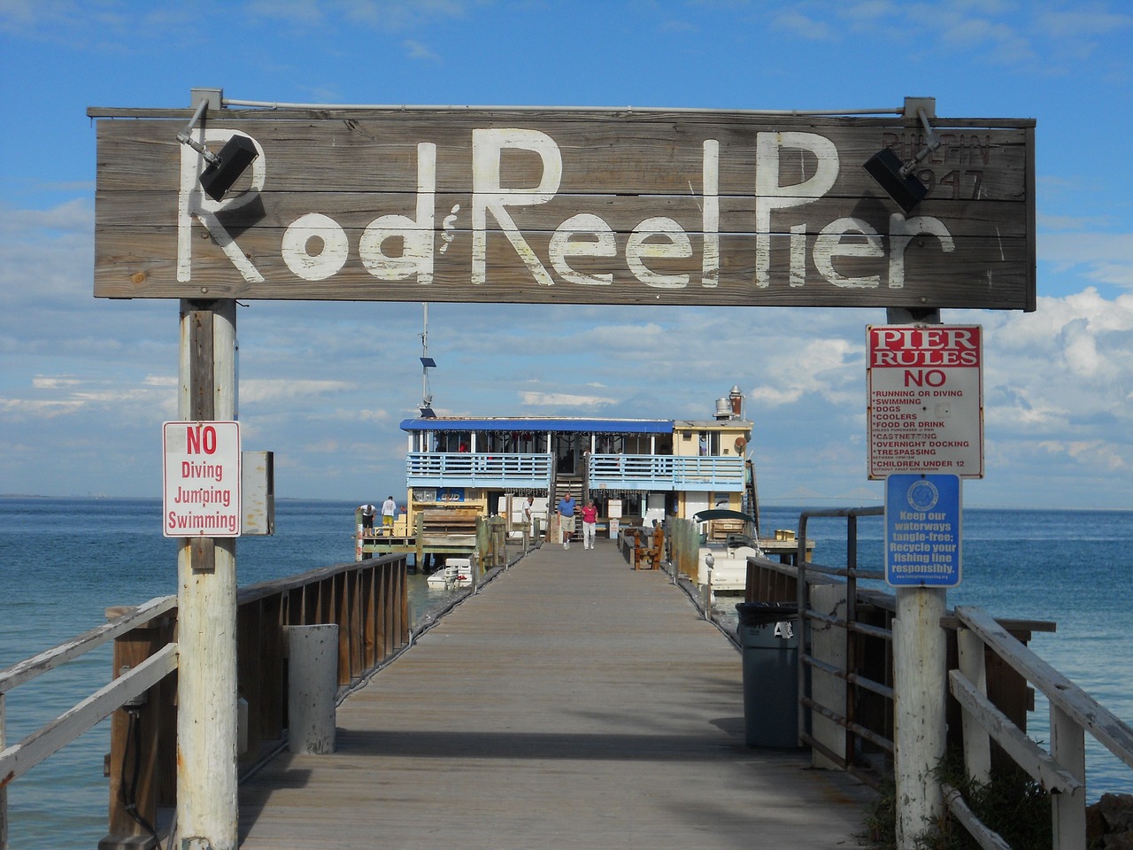 Wooden pier with Rod Reel Pier sign over Gulf water