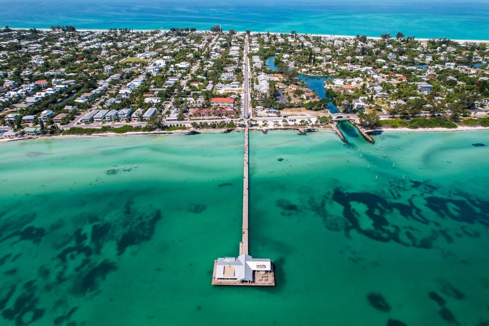 Sailboat anchored offshore near developed beach community