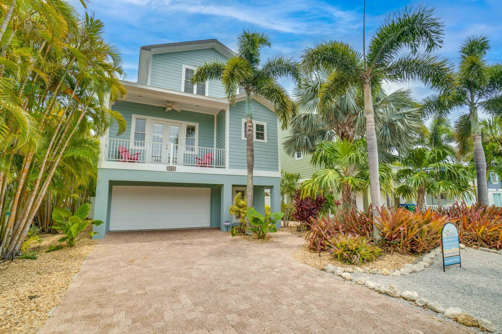 Two-story vacation home with palm trees and driveway