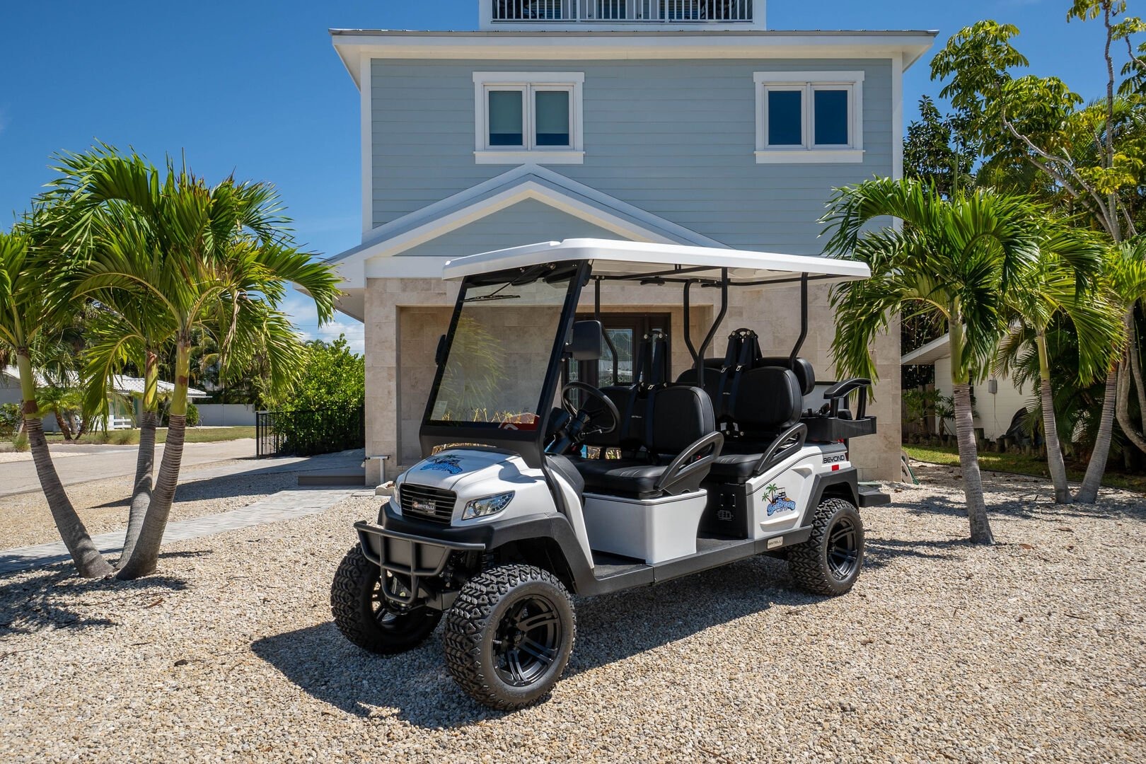 Vacation rental home with golf cart parked under palm trees