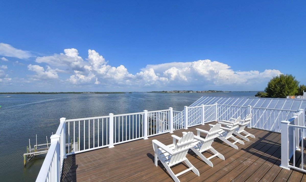 Wooden deck with white lounge chairs and water view