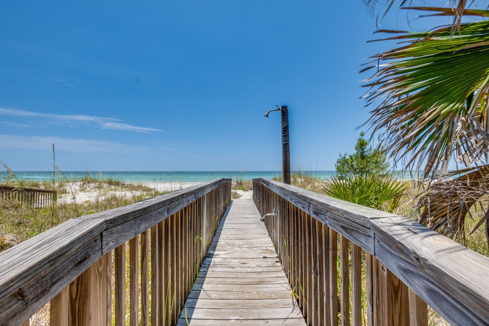 Wooden boardwalk extending toward beach with palm trees alongside