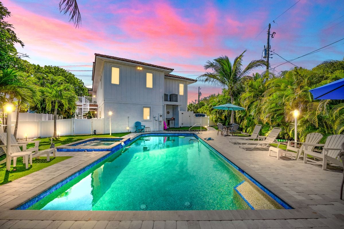 Vacation rental with illuminated pool and tropical landscape at dusk