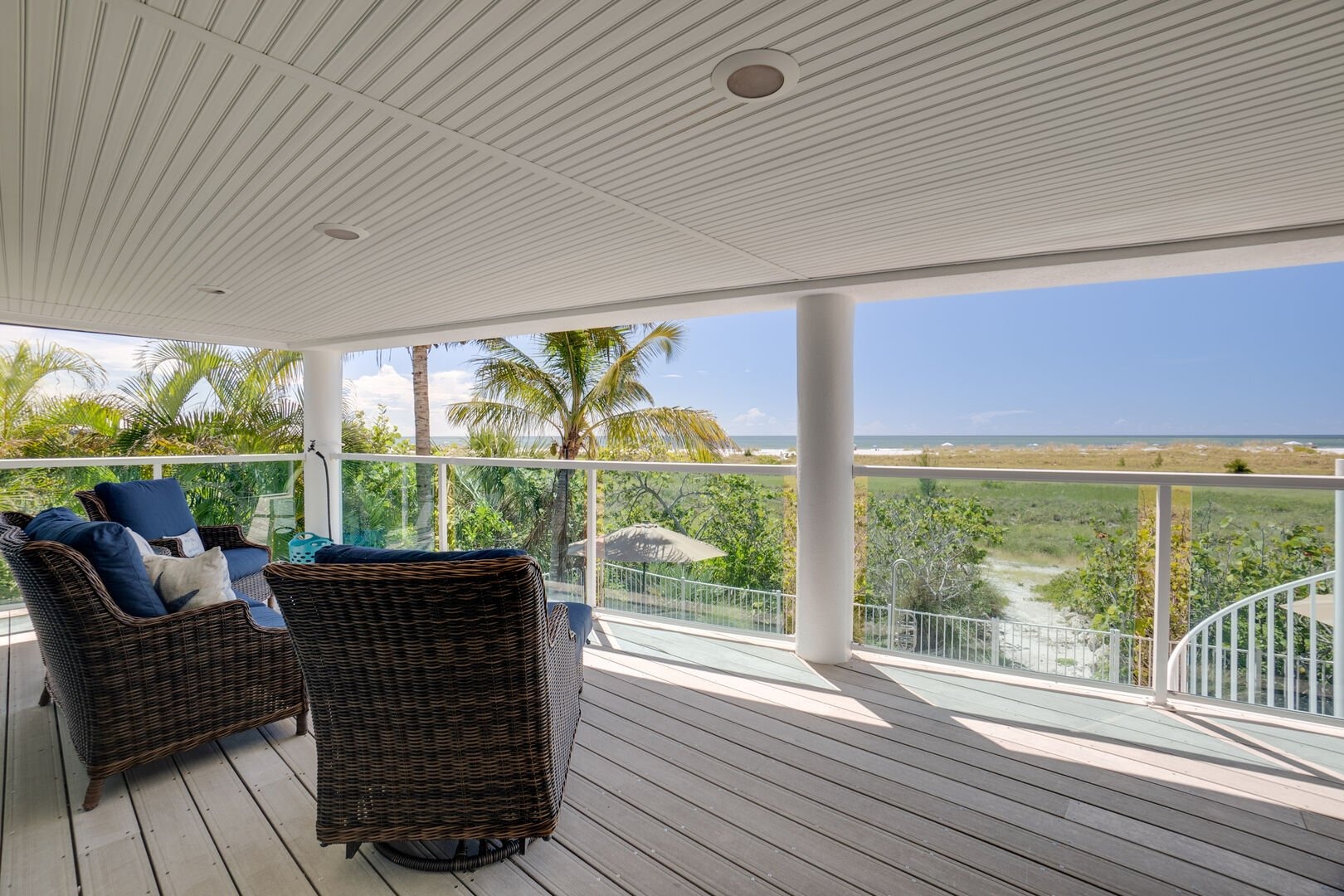 Covered patio with rattan furniture overlooking waterfront