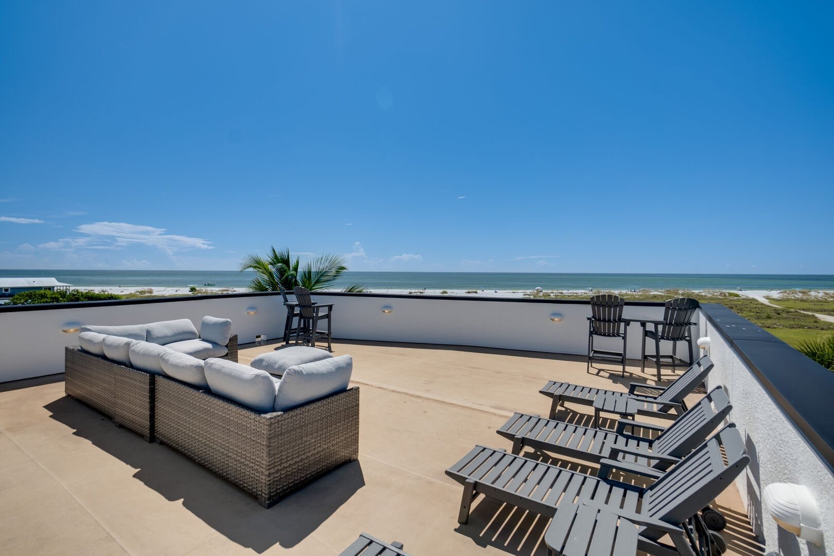 Rooftop seating area with lounge chairs overlooking coastal landscape