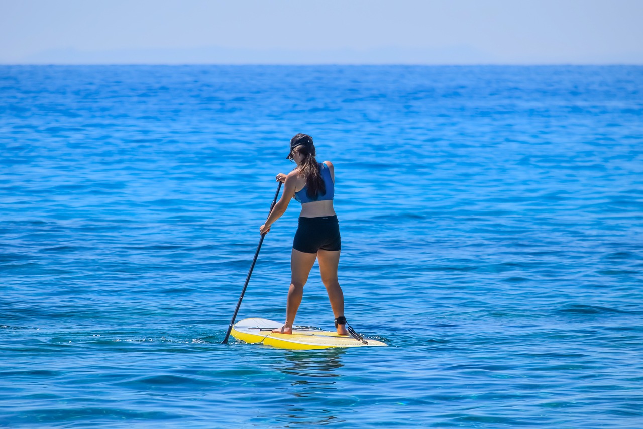 Woman paddleboarding on clear blue water