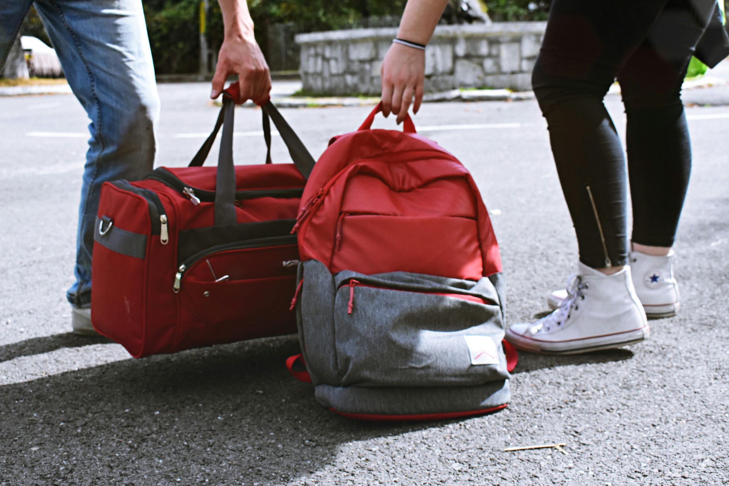 Three travelers carrying red and gray travel bags and luggage
