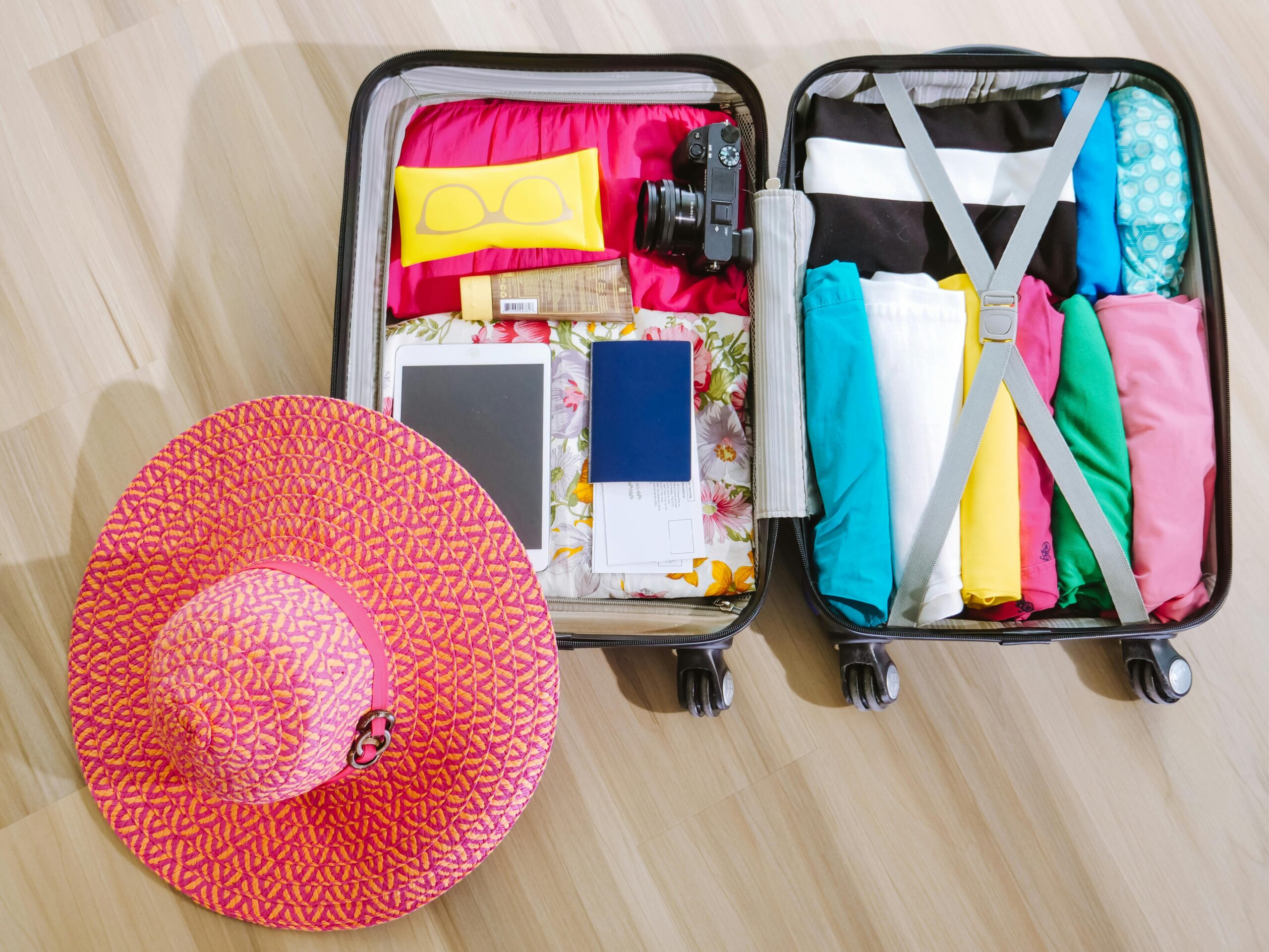 Two packed suitcases with beach hat on floor