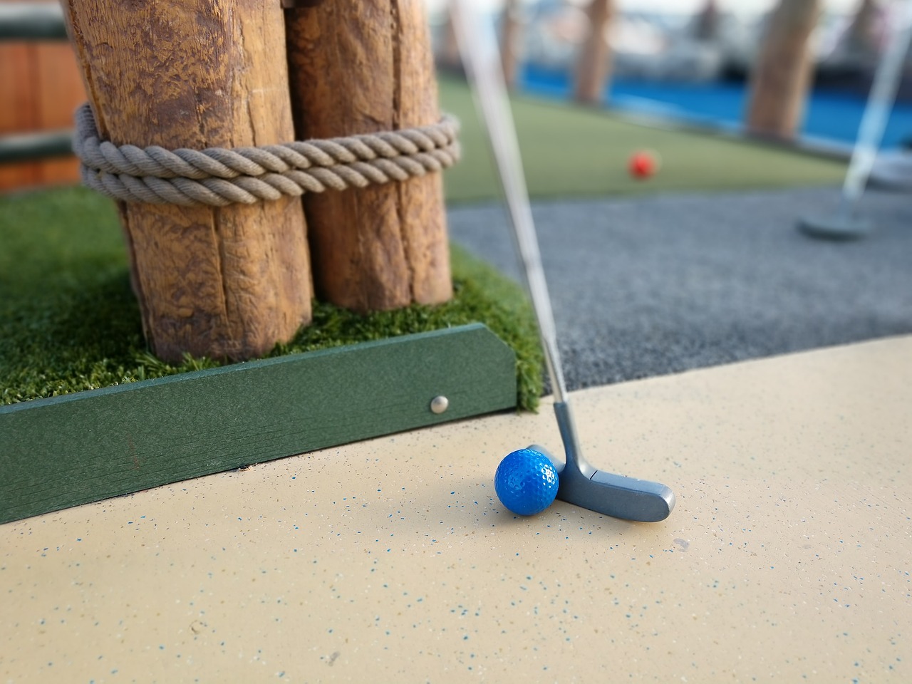 Mini golf putter and blue ball near hole