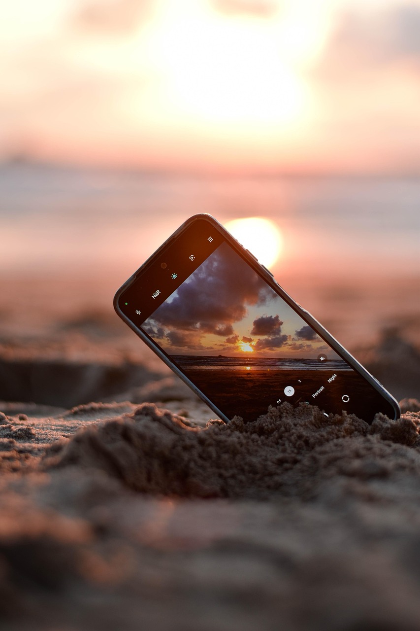Glass bottle resting on sand during golden hour sunset