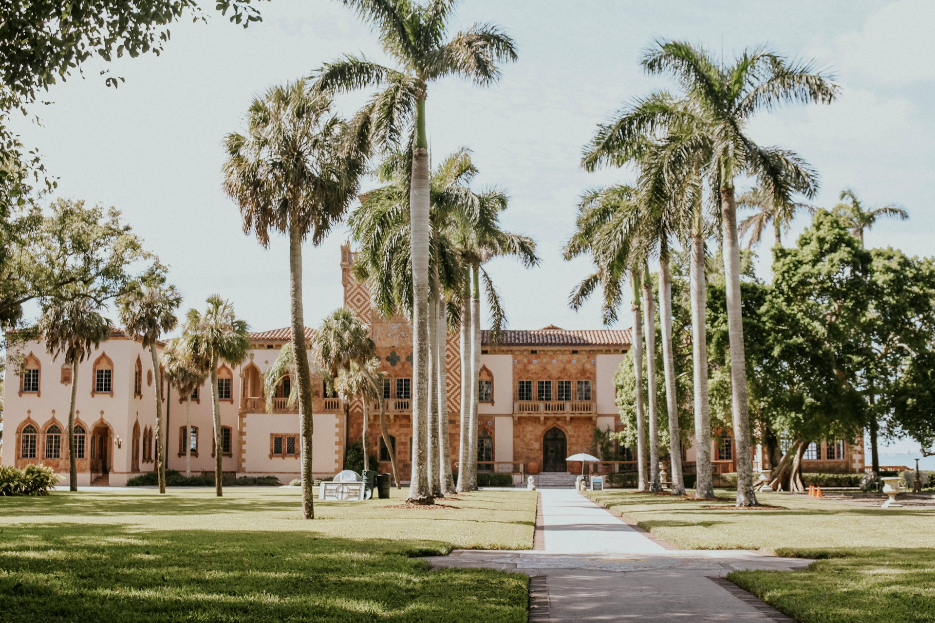 Grand historic pink mansion with tall palm tree-lined courtyard